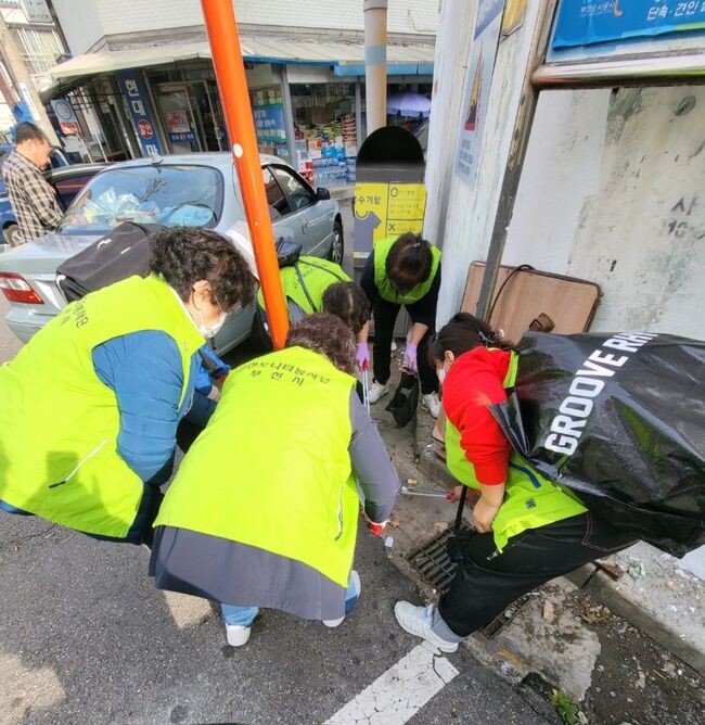 봉사단체 봉사자들이 하수구와 상가 주변 담배꽁초를 줍고 있다