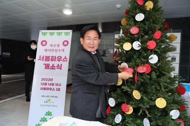 서봄하우스 개소식 기념 트리에 축하메시지를 달고 있는 박강수 마포구청장&nbsp;