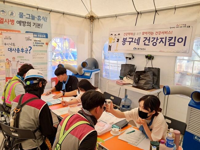 건설현장 야외천막에서 분야별 건강전문가가 일대일 건강상담을 진행하고 있다(2023. 8. 3.)
