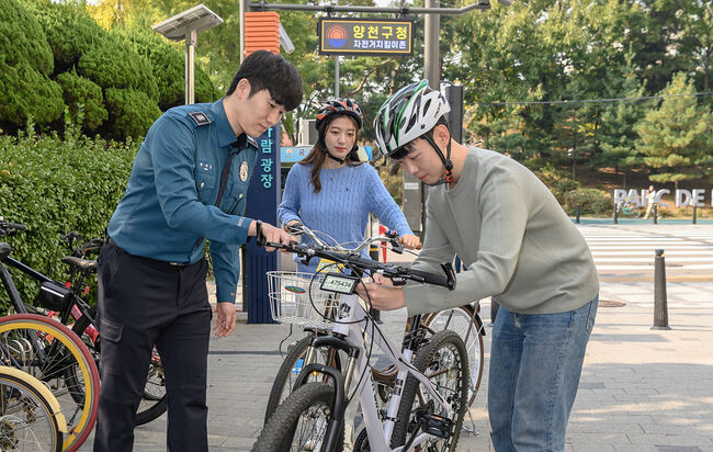 양천구 '자전거 지킴이 솔루션' 적용을 위해 자전거를 등록한 후 '자전거 지킴이 존'에서 전자칩이 내장된 자전거 번호판을 장착중인 구민의 모습