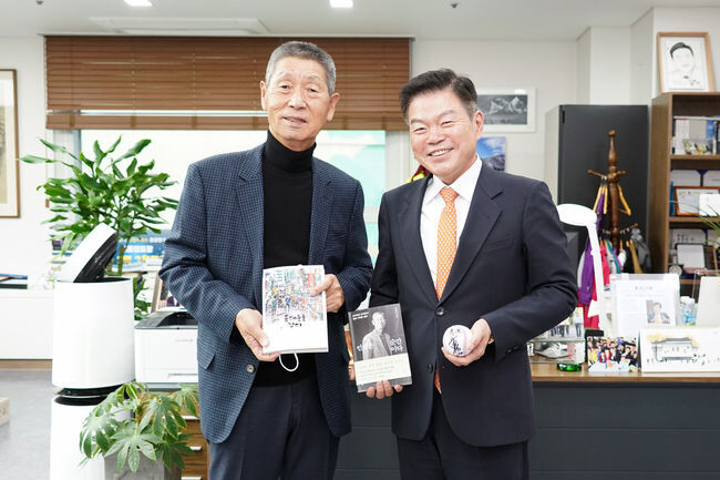 강연자인 김성근 감독과 이필형 동대문구청장이 저서를 교환하고 기념촬영을 하고 있다.