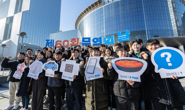 매년 12월 5일 개최되는 '무역의 날' 기념식 60주년을 맞아 서울 강남구 코엑스 광장에서 무역협회 임직원들이 시대별 주요 수출품(60년대: 오징어, 70년대: 의류, 80년대: 자동차, 90년대: 반도체, 00년대: 휴대폰, 10년대: K-food)을 들고 기념촬영을 하고 있다.