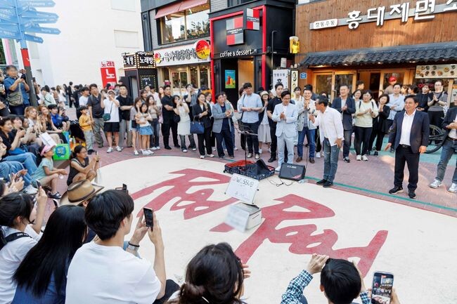 해 기반시설 개선이 이루어진 홍대 레드로드에서 시민들이 버스킹 음악 공연을 즐기고 있다
