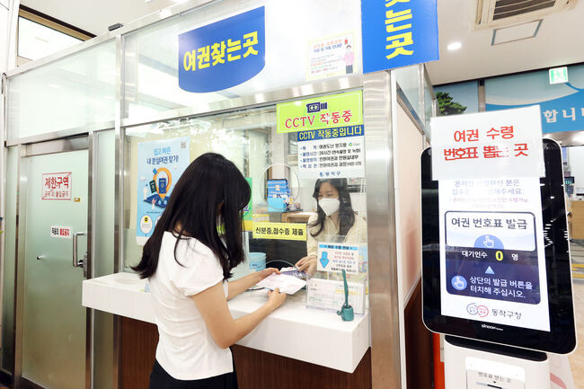 동작구 민원실에서 민원인이 여권과 여권 케이스를 교부 받고 있는 모습