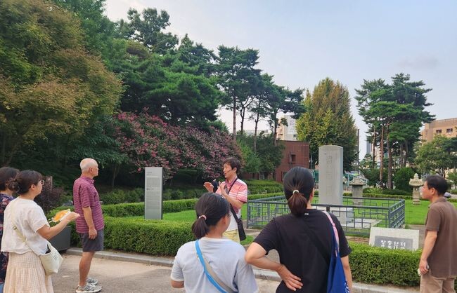 시민들이 장충단비 앞에서 문화해설사에게 설명을 듣고 있다.